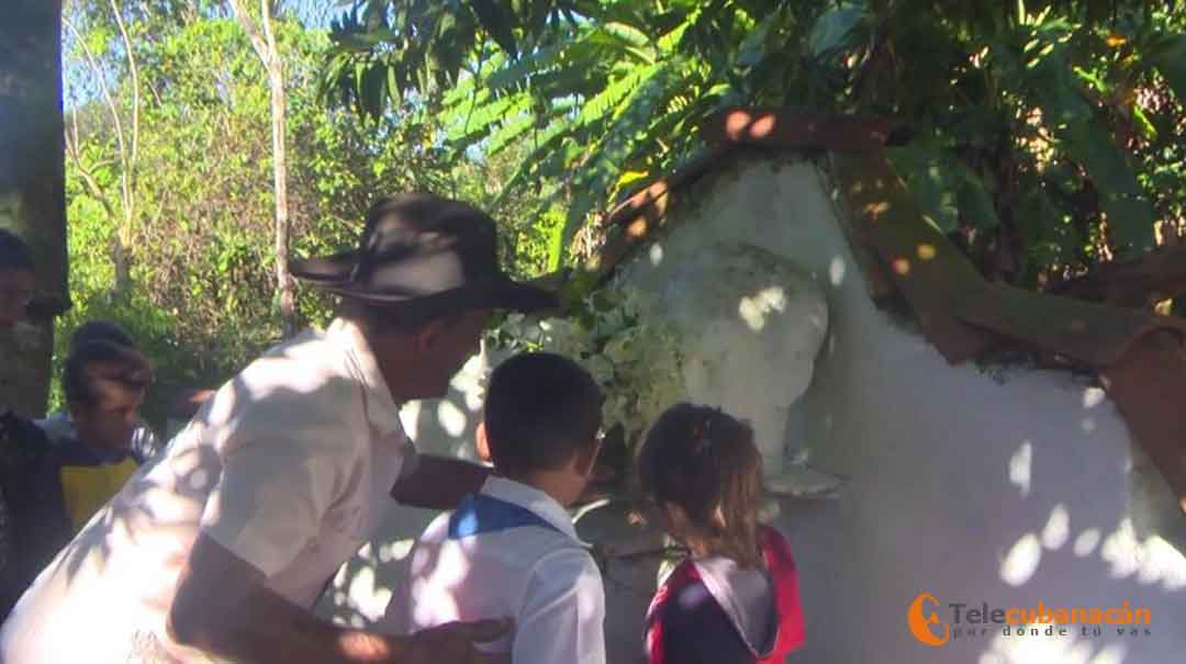 Genaro, junto a los niños, coloca flores blancas al Apóstol.